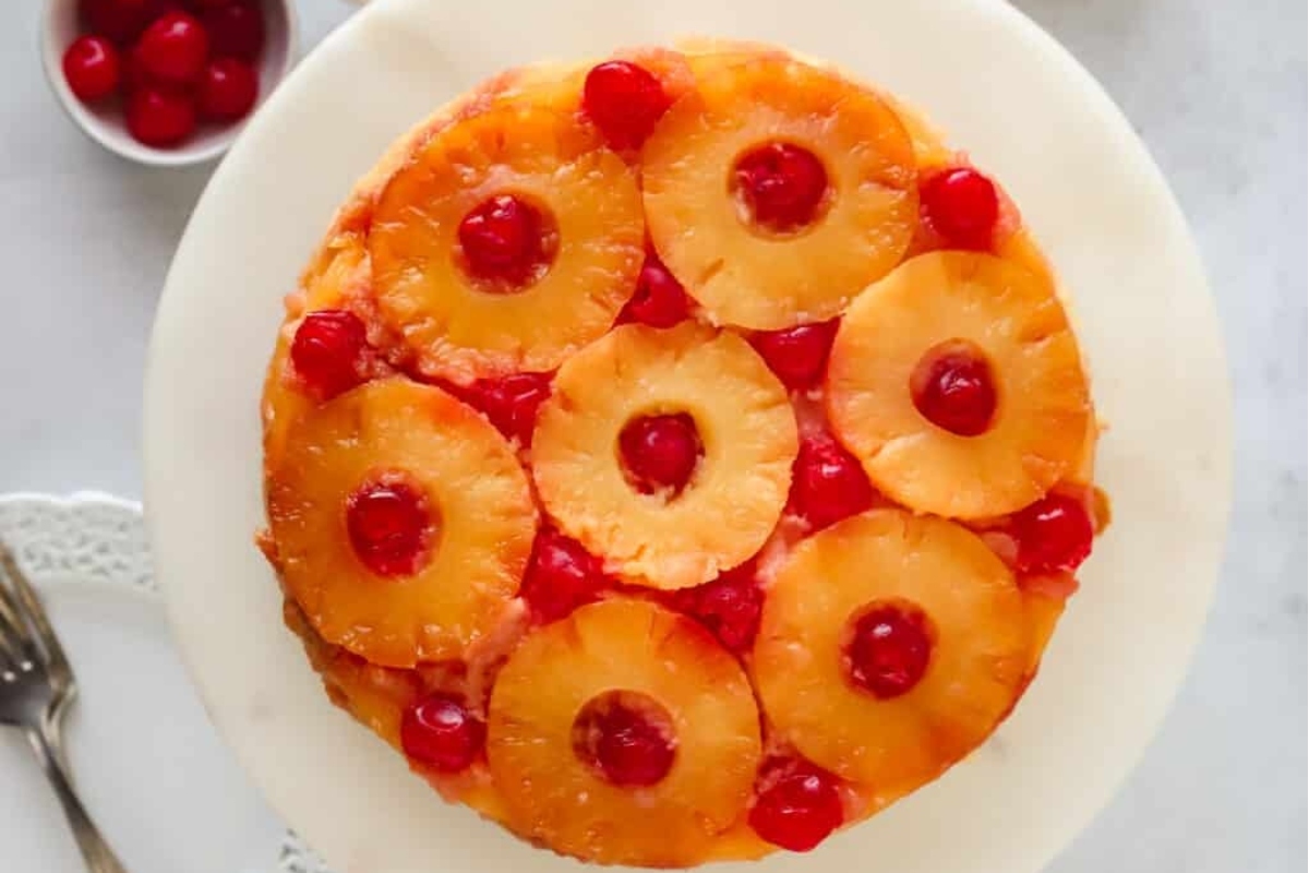 A pineapple upside down cake with cherries on top.