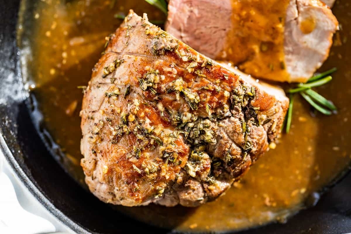 A piece of meat with herbs on top of it.