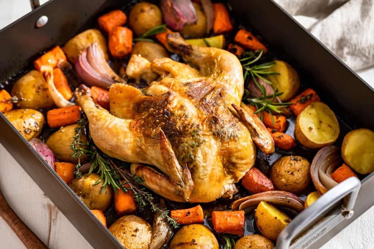 Roasted chicken with carrots and potatoes in a pan.