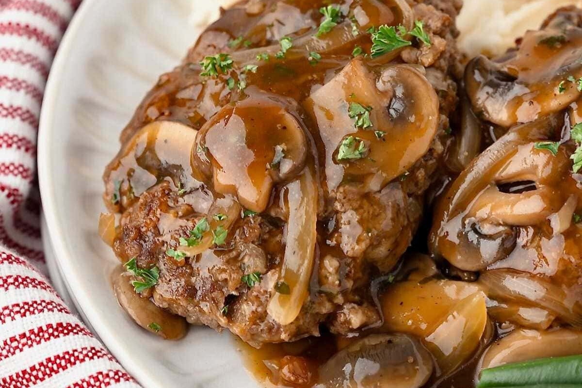 A plate of meat with gravy and mushrooms.