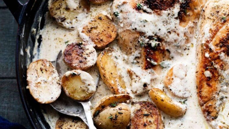 Chicken with potatoes and gravy in a skillet.