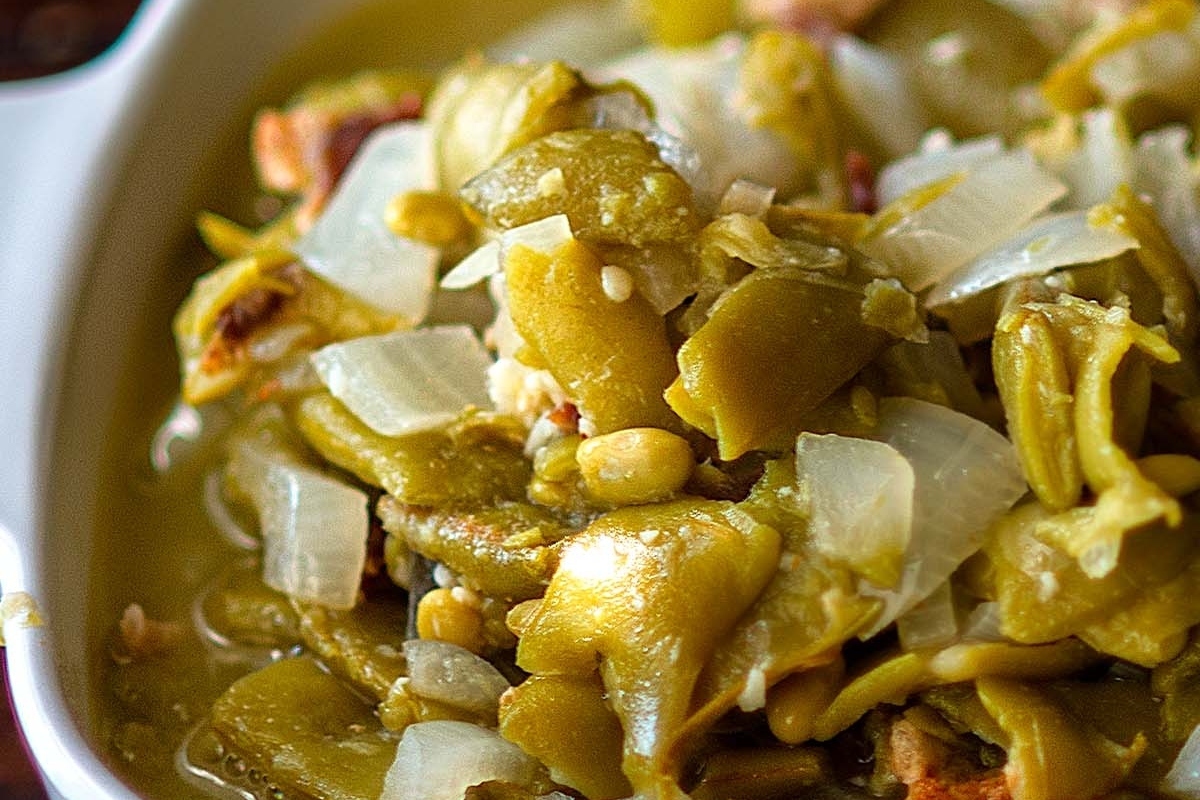 Close-up of a dish with green beans and sliced onions.