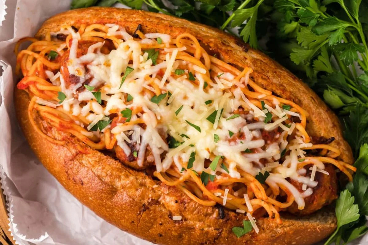 A spaghetti sandwich topped with melted cheese and recipes featuring noodles, served in a basket.