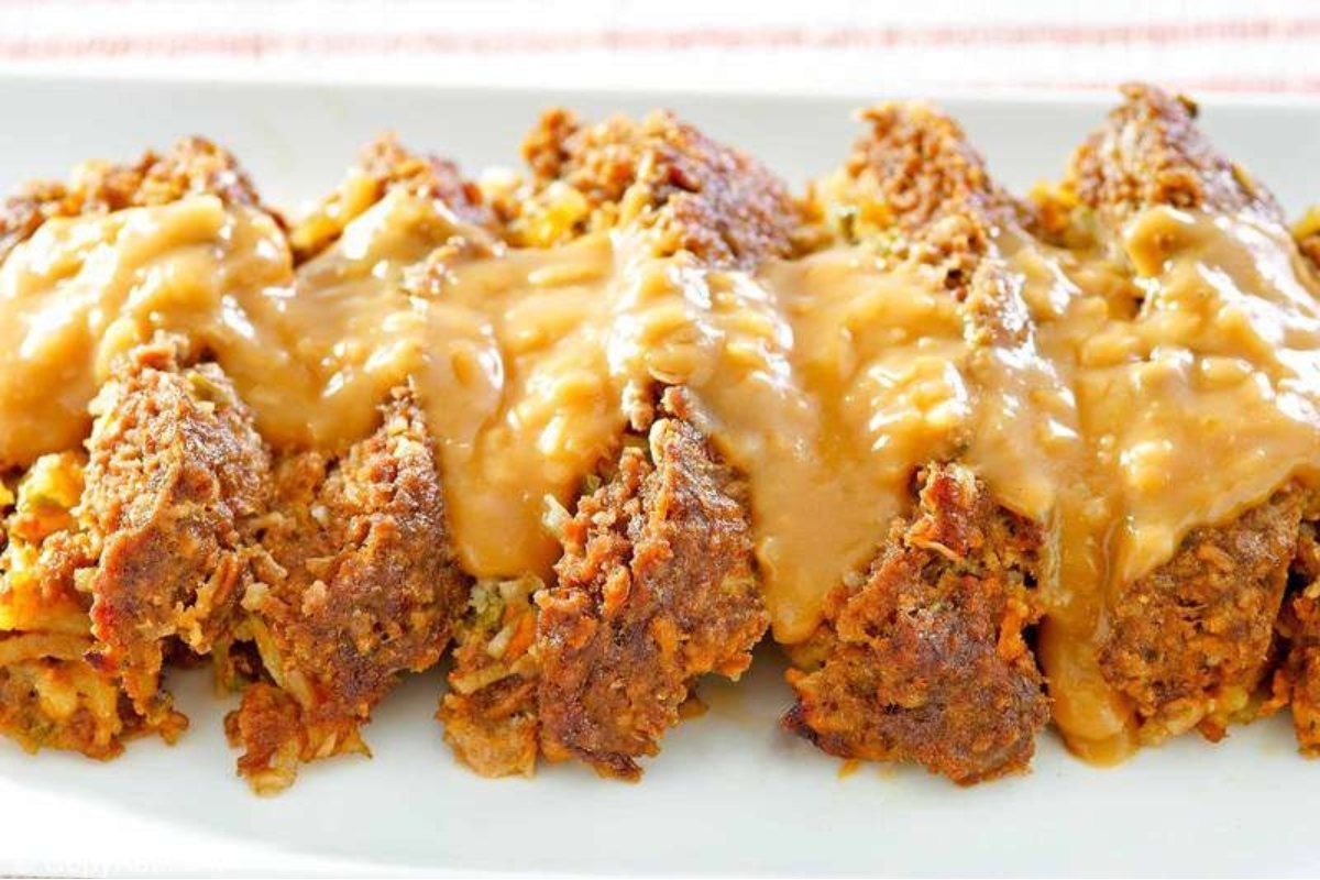 A plate of meatloaf smothered in a creamy gravy sauce.