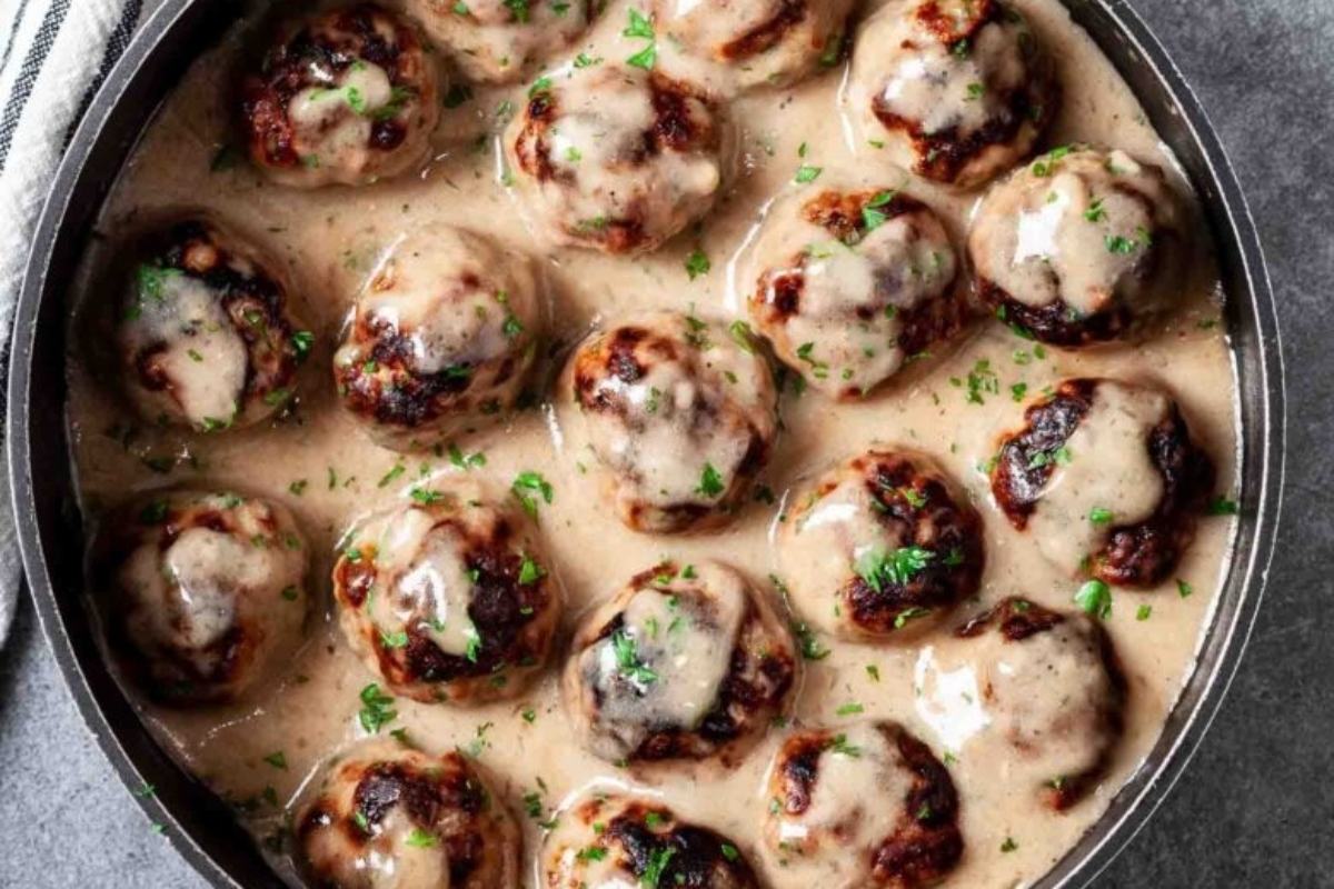A pan of swedish meatballs topped with creamy sauce and garnished with parsley.