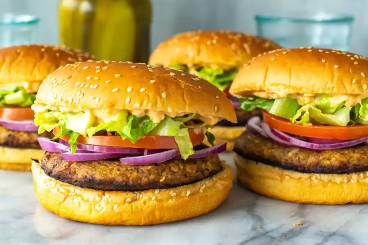 Four veggie burgers are sitting on a marble table.