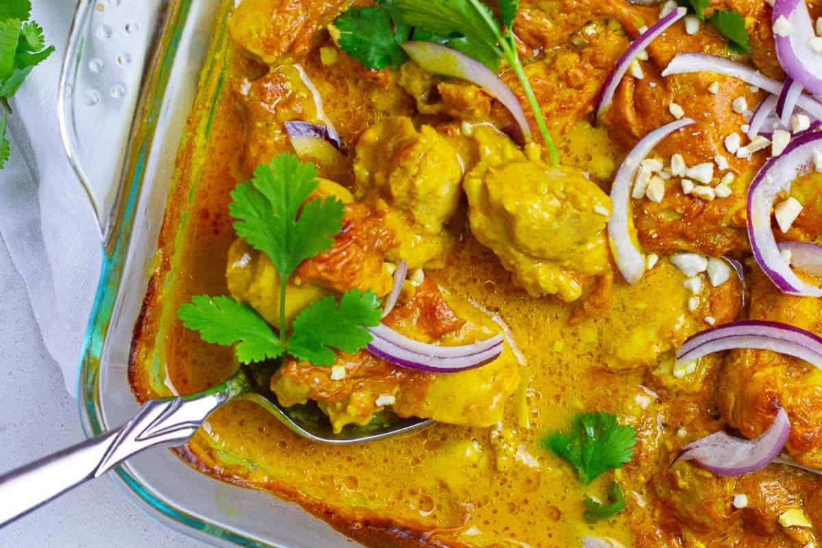 A colorful curry dish garnished with fresh cilantro and red onion slices.