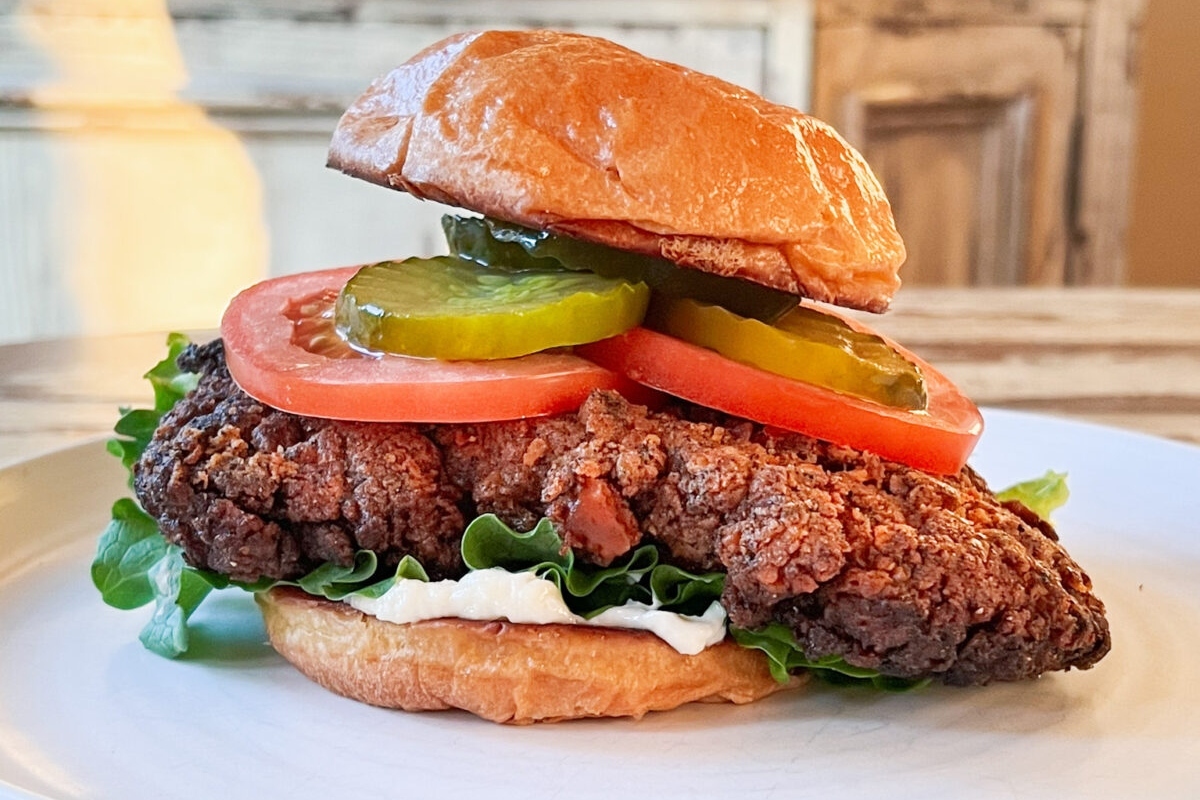 A pork tenderloin sandwich on a white plate.