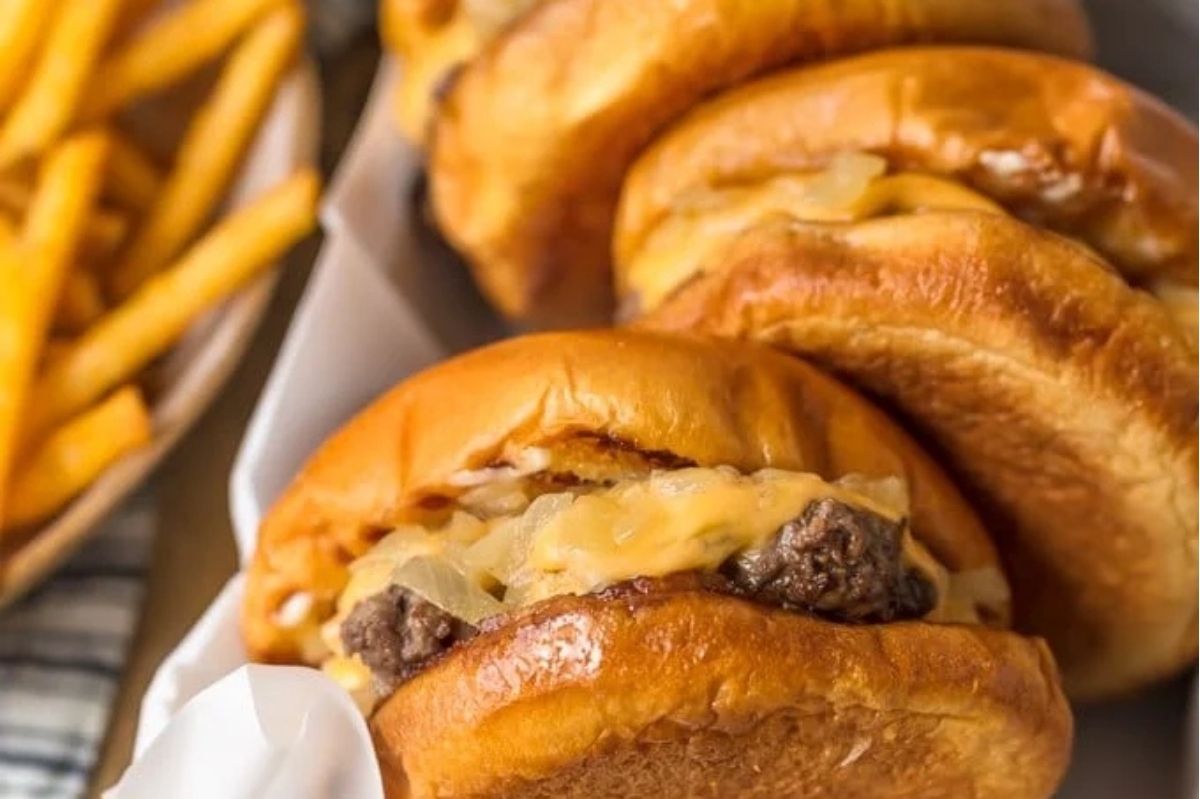 Three burgers on a plate with french fries.