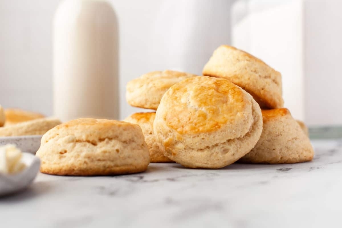 Golden-brown biscuits on a marble countertop with a bottle of milk in the background.