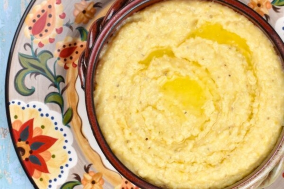 A bowl of creamy polenta with a drizzle of olive oil, served on a decorative floral plate.