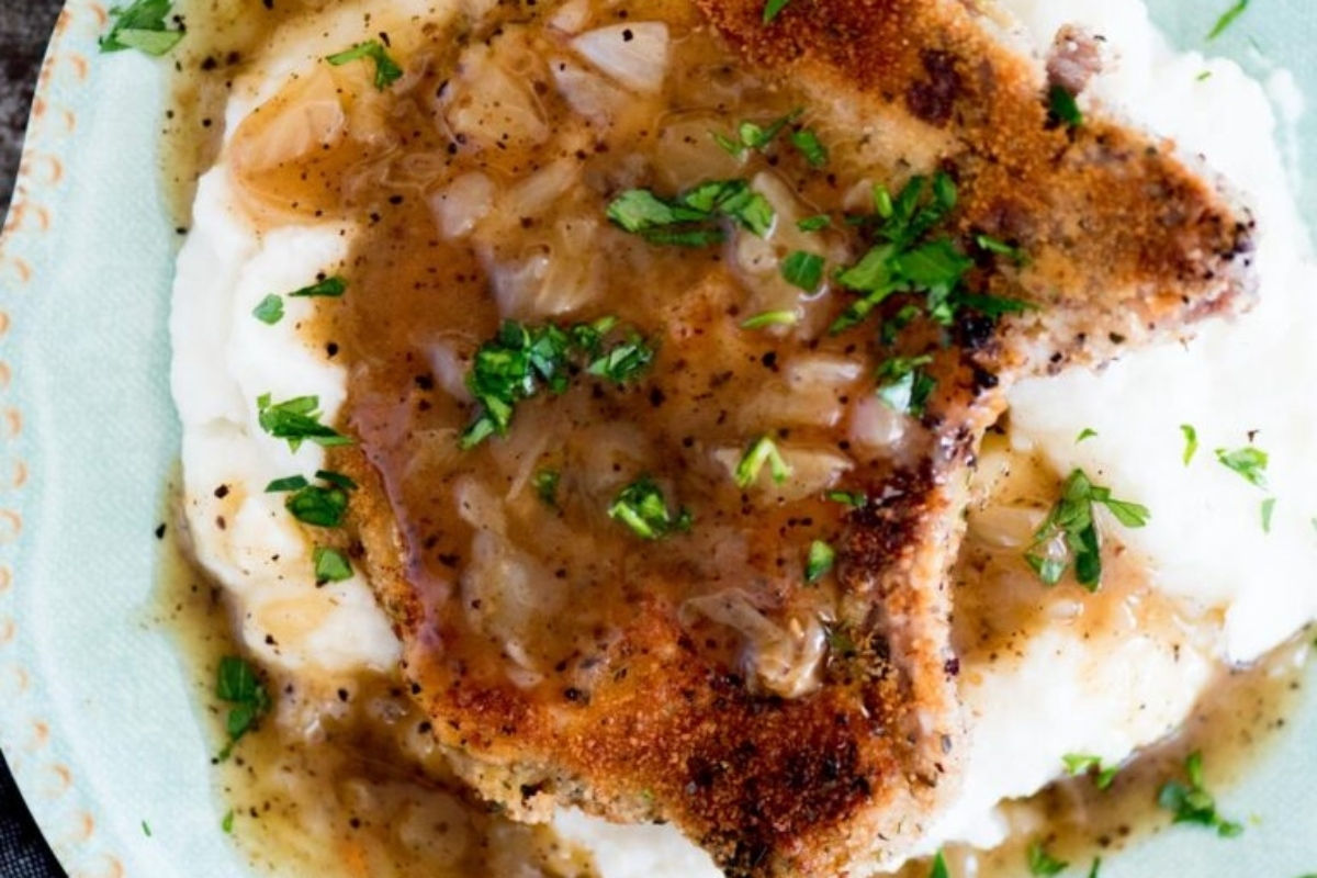Breaded pork cutlet served over mashed potatoes and topped with onion gravy and parsley.