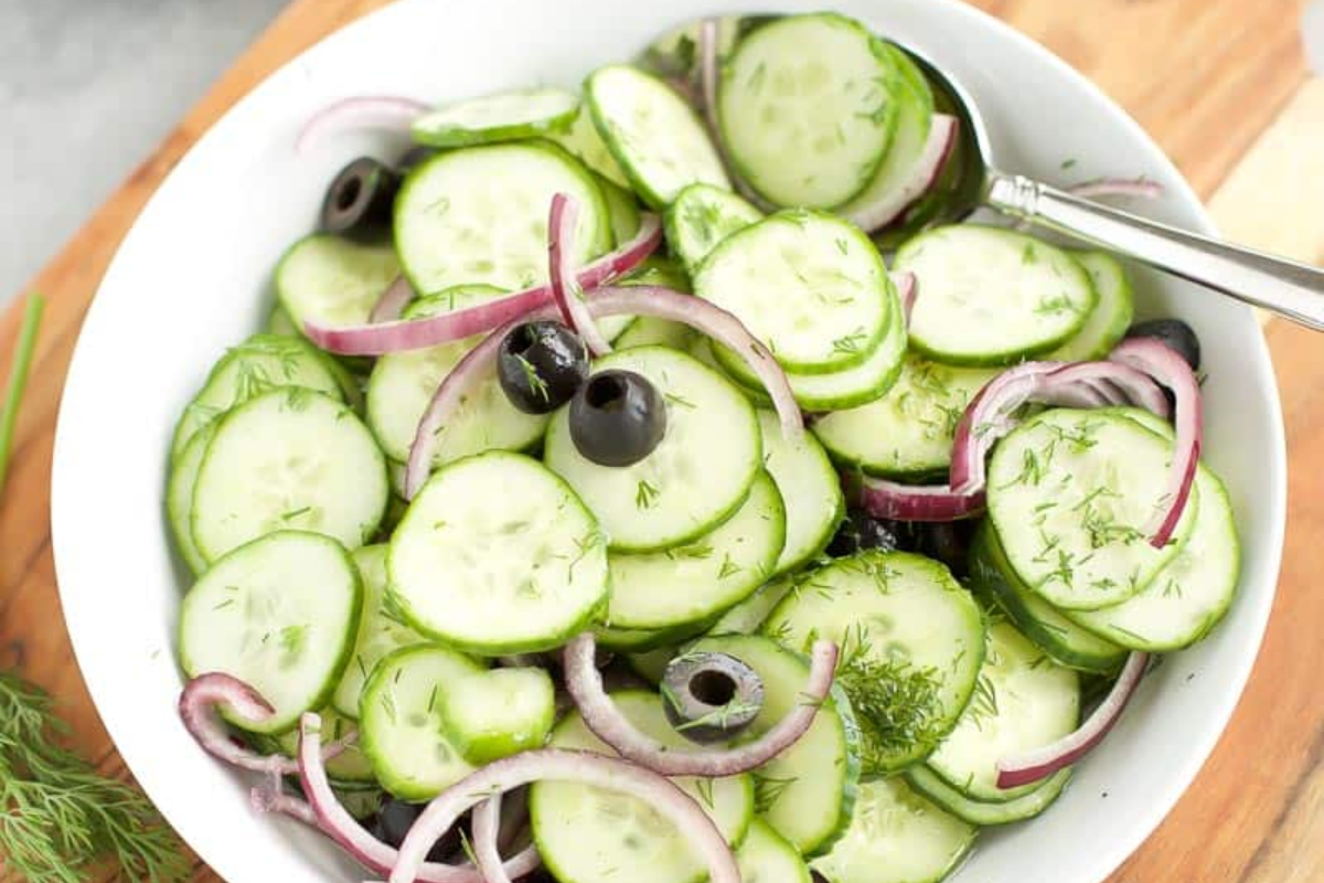 A bowl of cucumber salad with olives and onions, perfect for olive lovers.