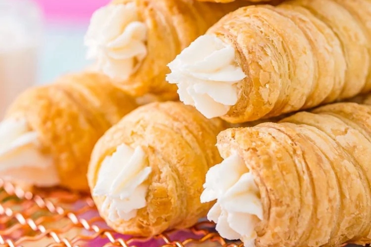 A stack of cream filled croissants on a rack.
