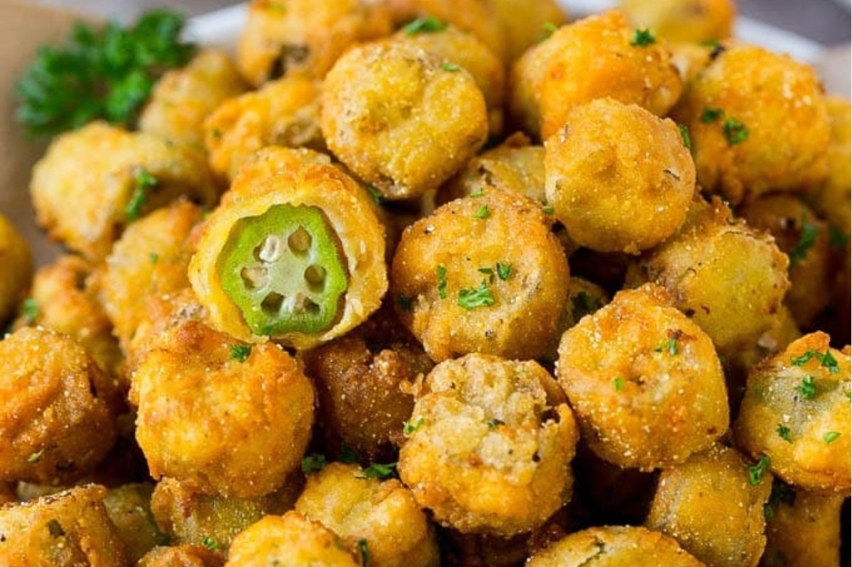 A close-up of golden-brown fried okra garnished with parsley.