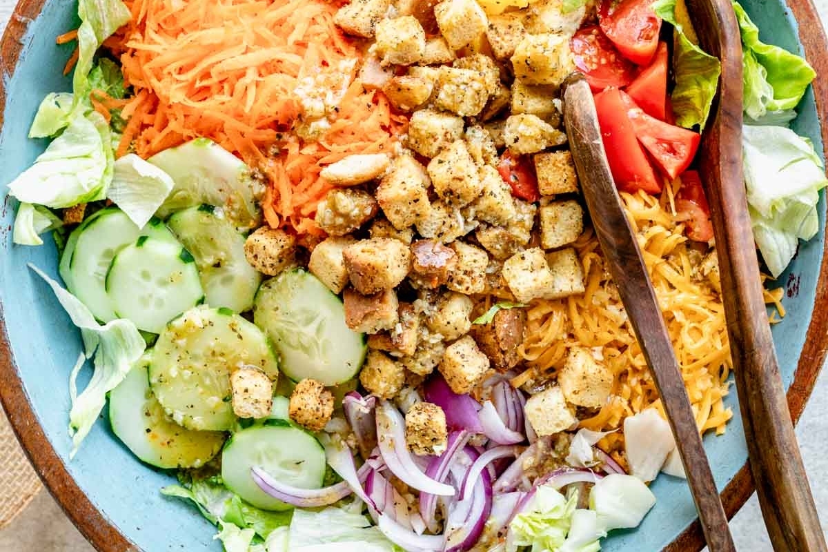 A bowl of salad with croutons, tomatoes and cucumbers.