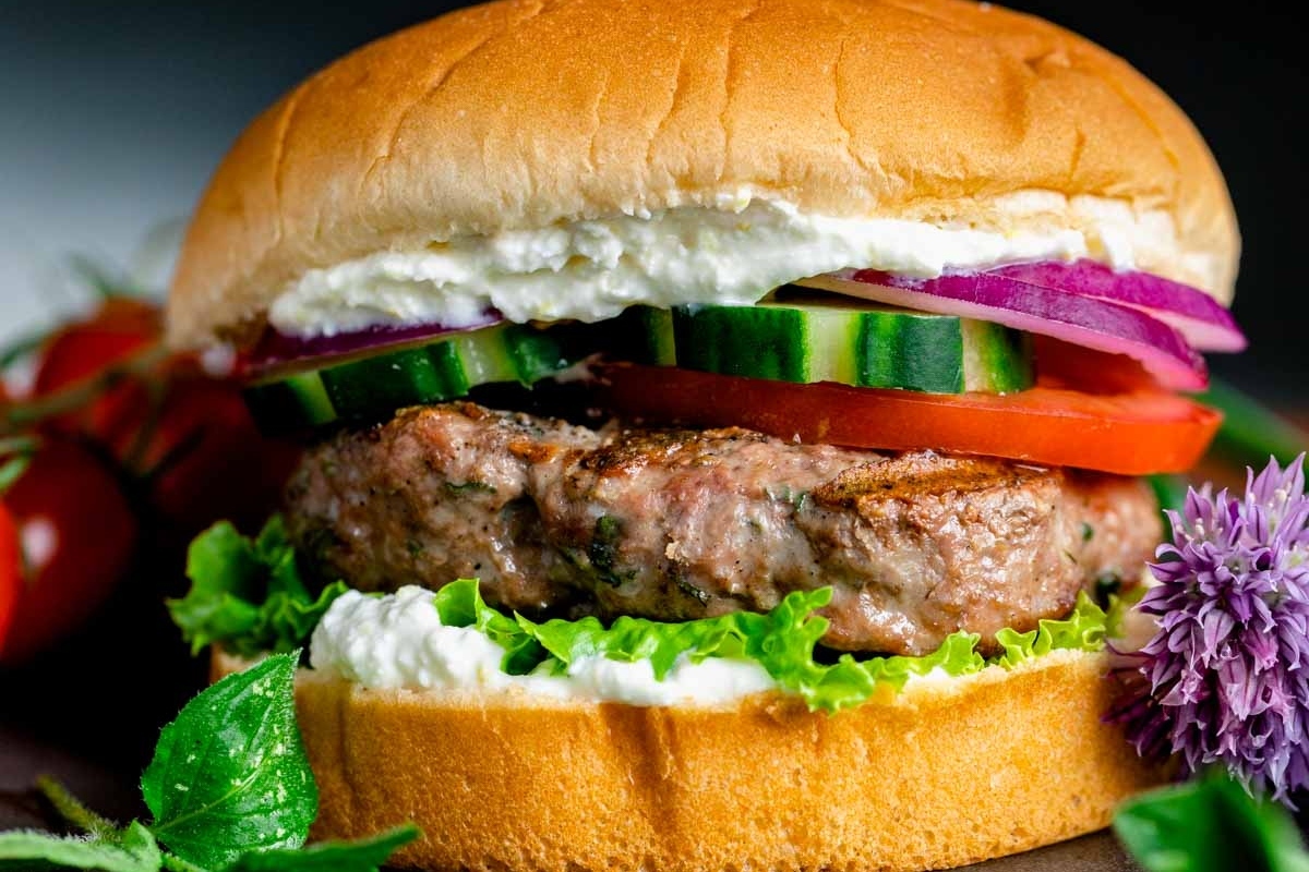 A burger with lettuce, tomatoes and cucumbers.