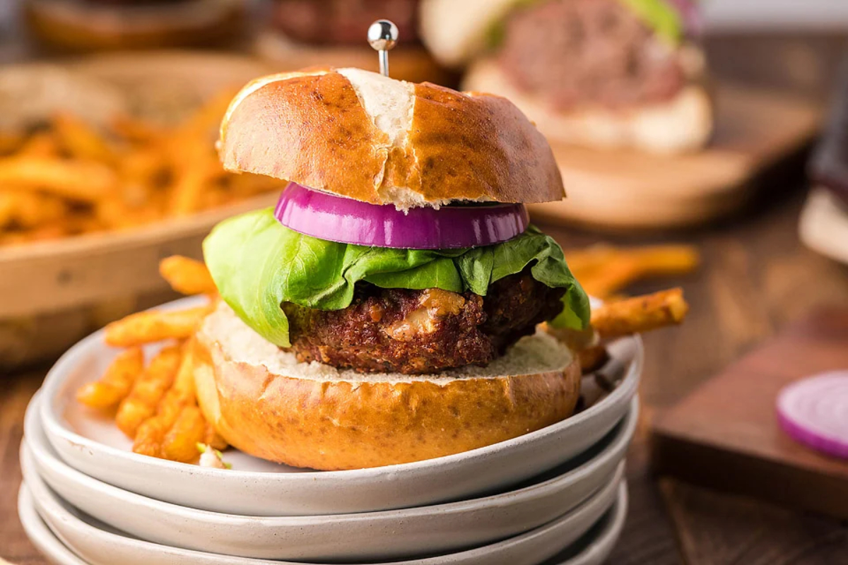 A burger on a plate with fries on the side.