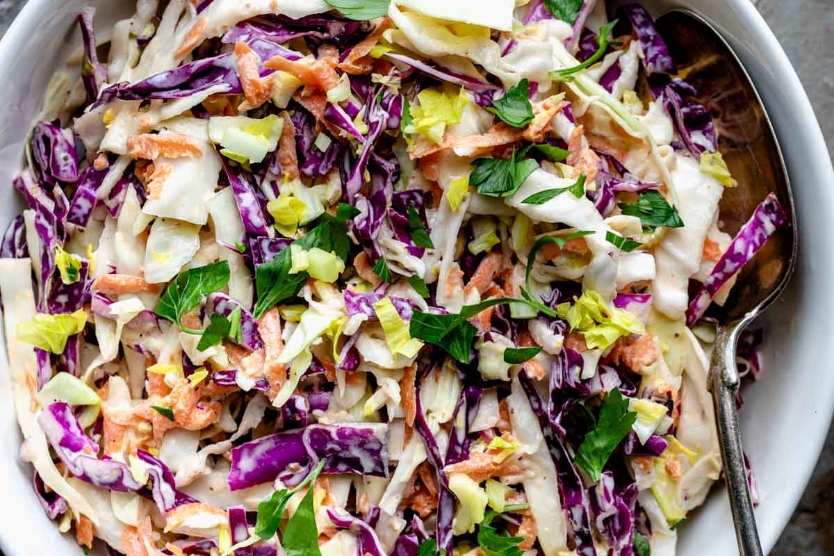 Cole slaw in a white bowl with a spoon.