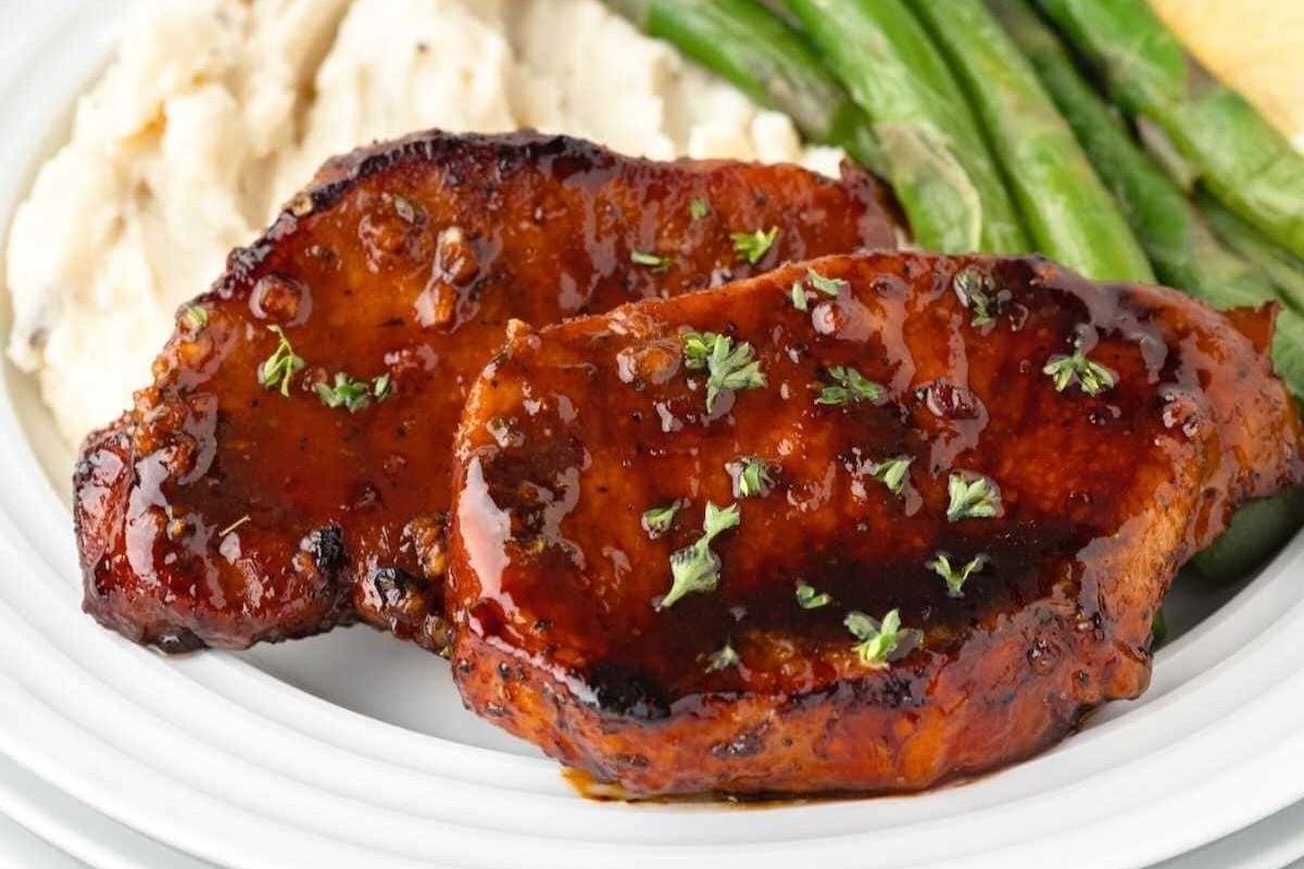 Bbq pork chops on a plate with green beans and mashed potatoes.