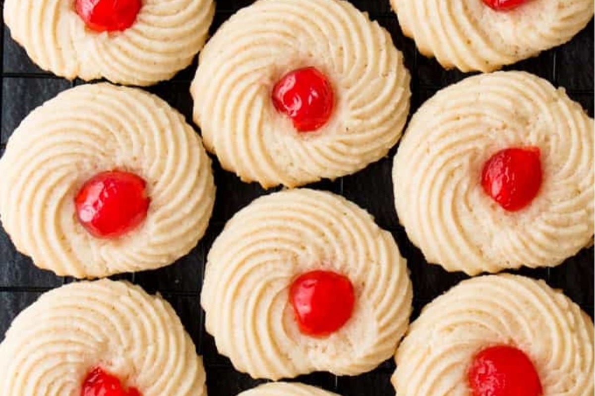A tray of cookies with cherries on it.
