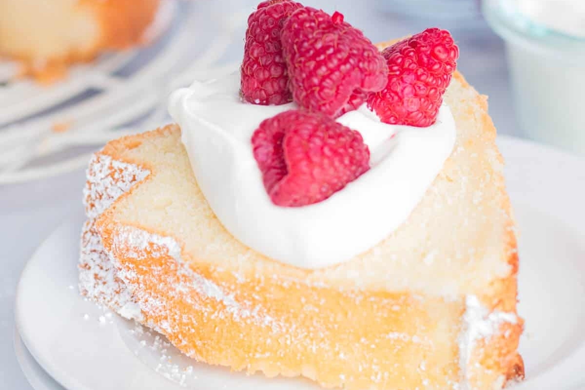 A slice of pound cake with whipped cream and raspberries.