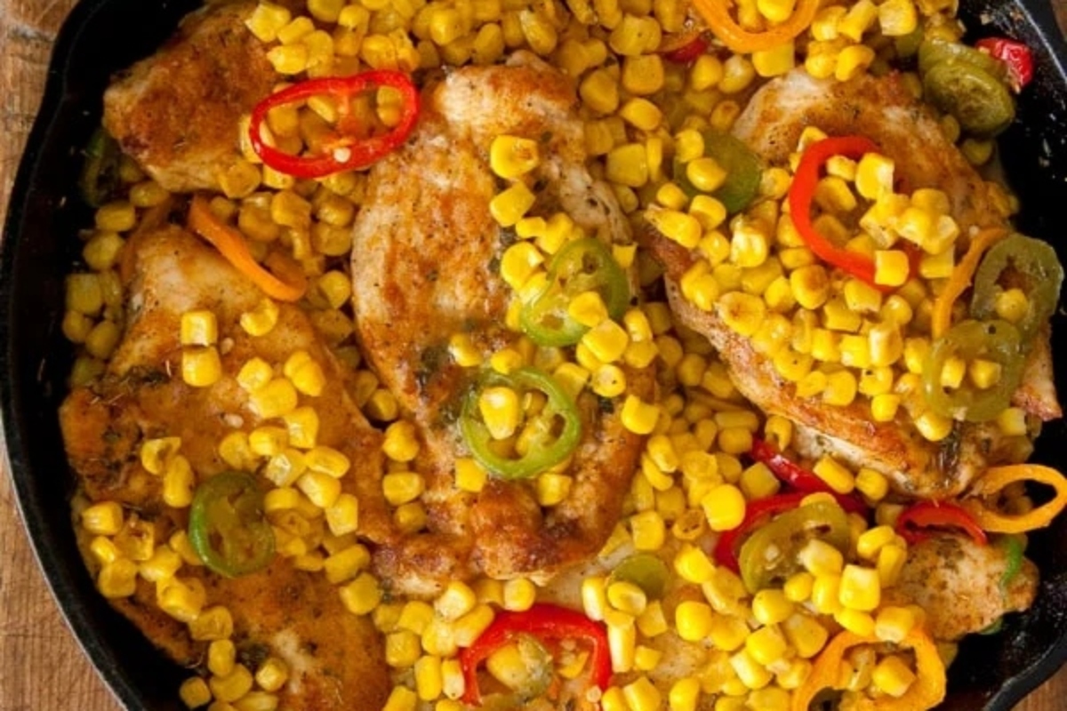 Pan-fried chicken with corn and sliced bell peppers.