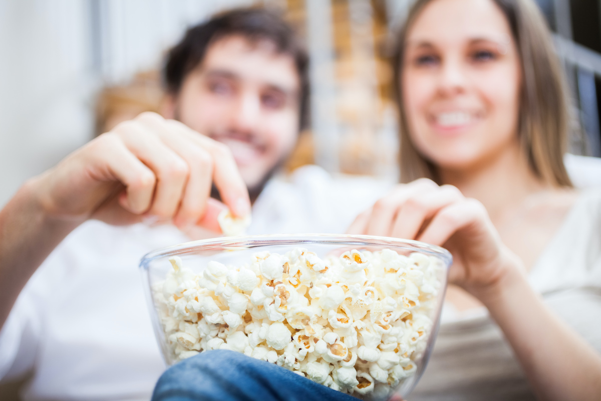 Young couple eating popcorn while watching a movie