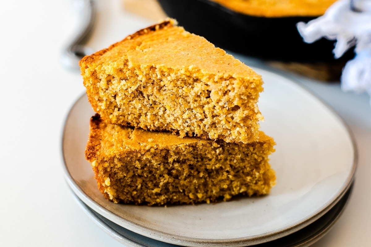 Two slices of corn bread on a white plate.