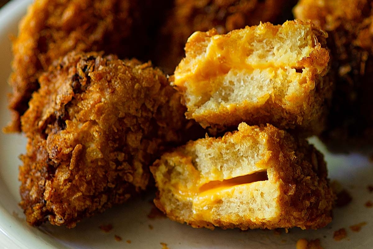 Fried cheese-stuffed snacks on a plate with a melted cheese filling visible.