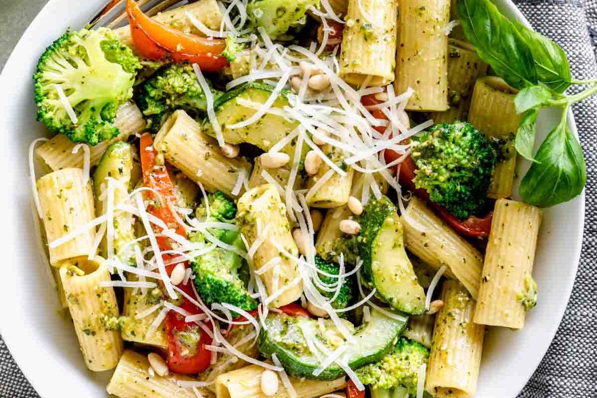 A bowl of pesto pasta with broccoli and parmesan cheese.