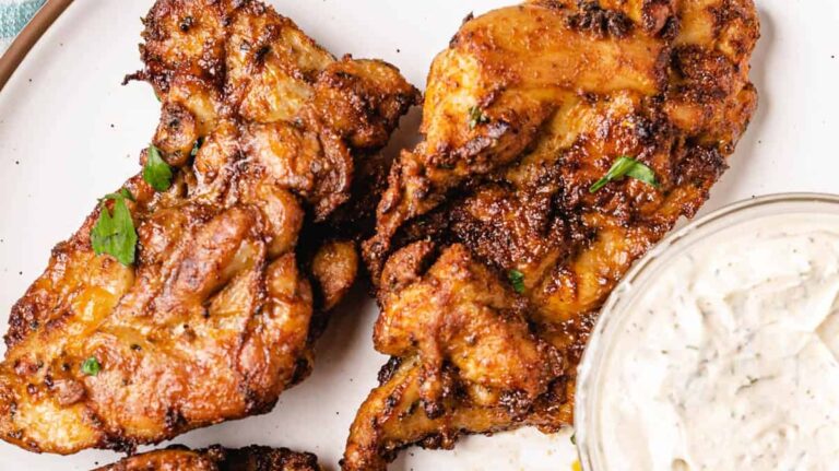 Chicken wings on a plate with a dipping sauce.