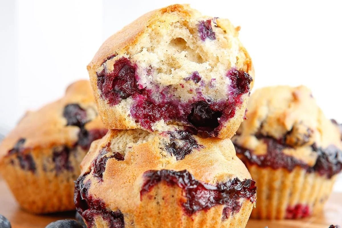 A pile of muffins with top one missing a bite.