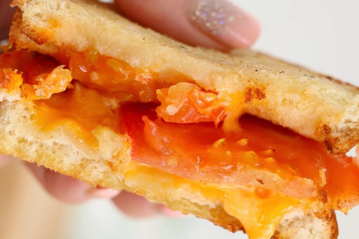 Half of a grilled cheese held in the air.