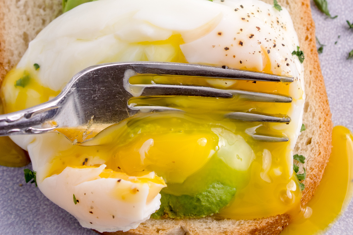 Fork cutting into egg with runny yolk.