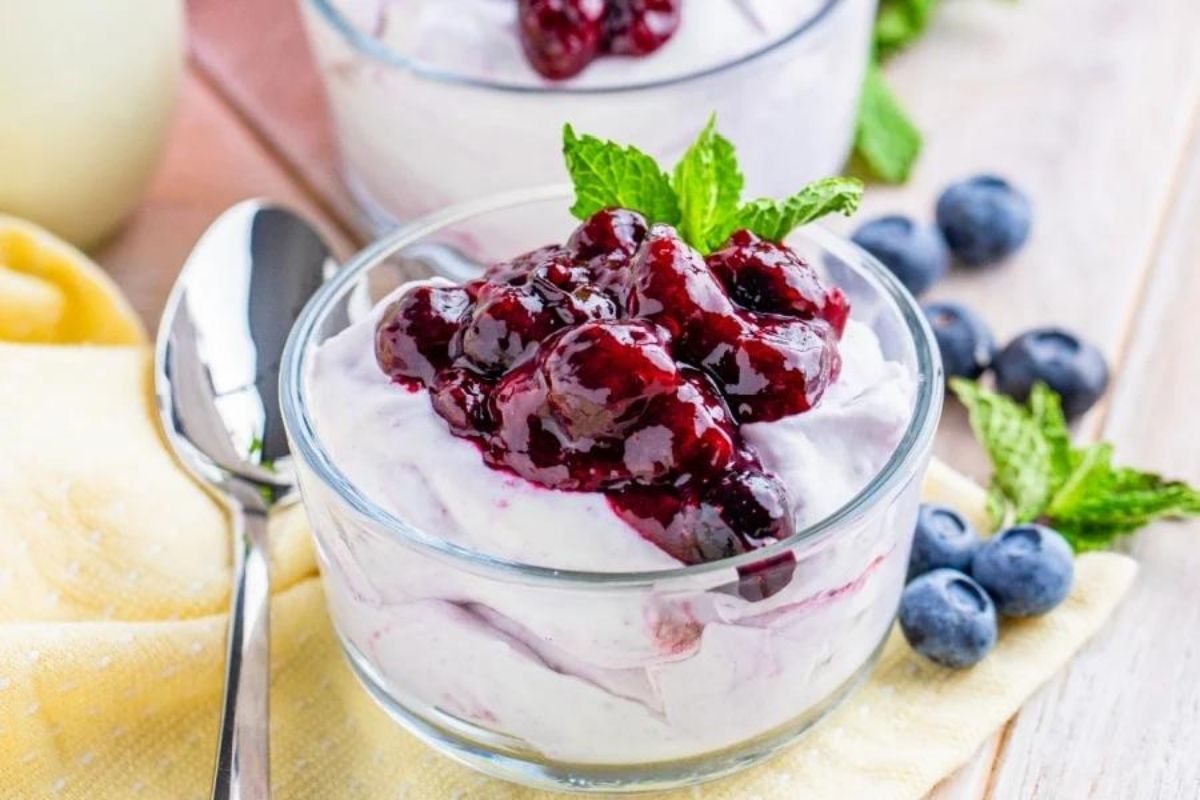 Closeup of dessert in clear bowl with blueberries on top.