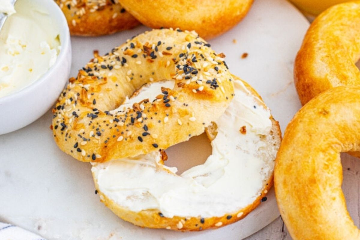 A sliced bagel with cream cheese on half.