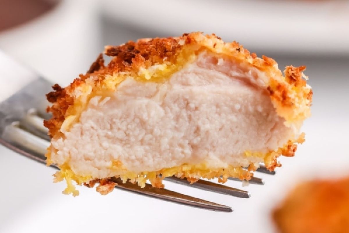 A close-up of a breaded chicken piece being held by a fork, showcasing its texture and cooked interior, perfect for air fryer dinner recipes.