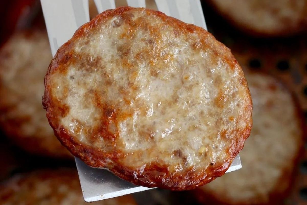 A sausage pattie on a spatula.
