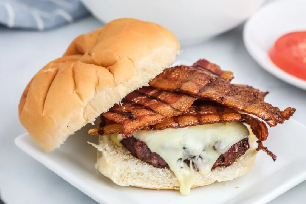 A stack of smoked bacon on a white plate, served with condiments in the background.