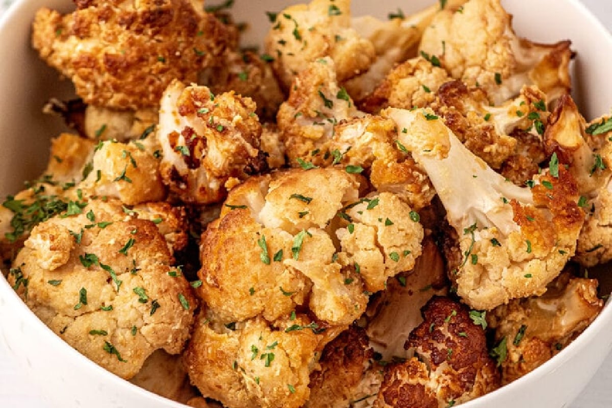 A white bowl filled with roasted cauliflower florets, garnished with chopped herbs, makes an ideal side for smoked dinners.