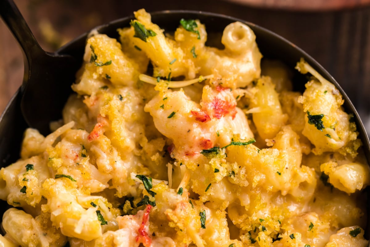 Close-up of baked macaroni and cheese topped with parsley and breadcrumbs in a black bowl—this must-try side dish is perfect for smoked dinners.