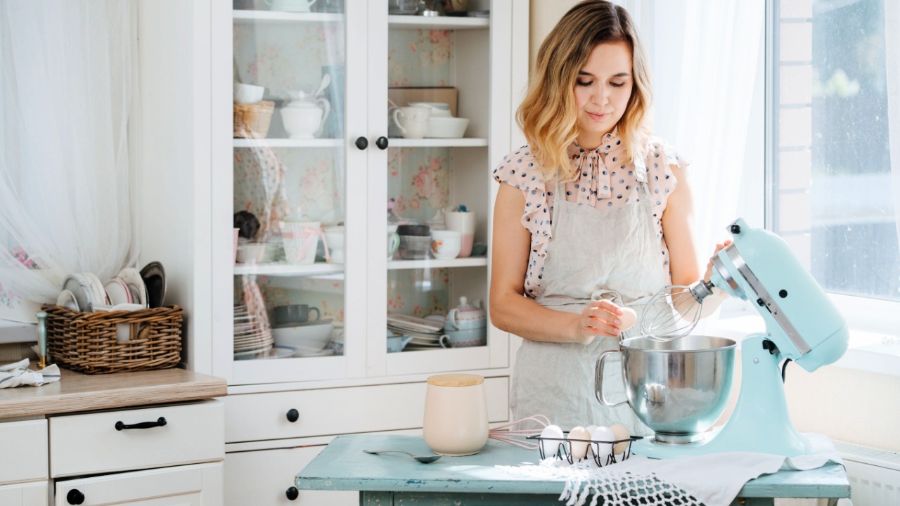 woman preparing dough in a food processor while standing in a bright kitchen