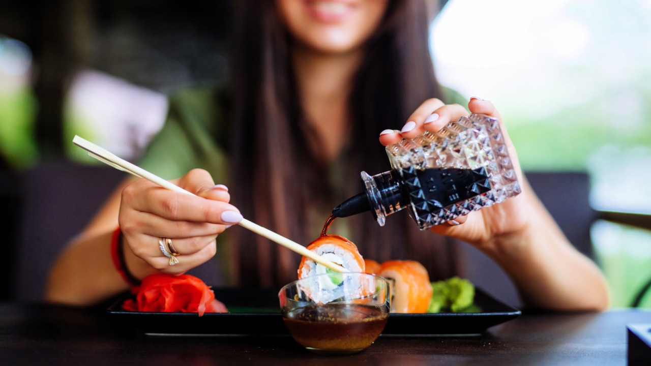 woman pouring sauce on sushi