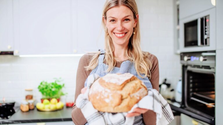 Happy woman holding homemade sourdough bread